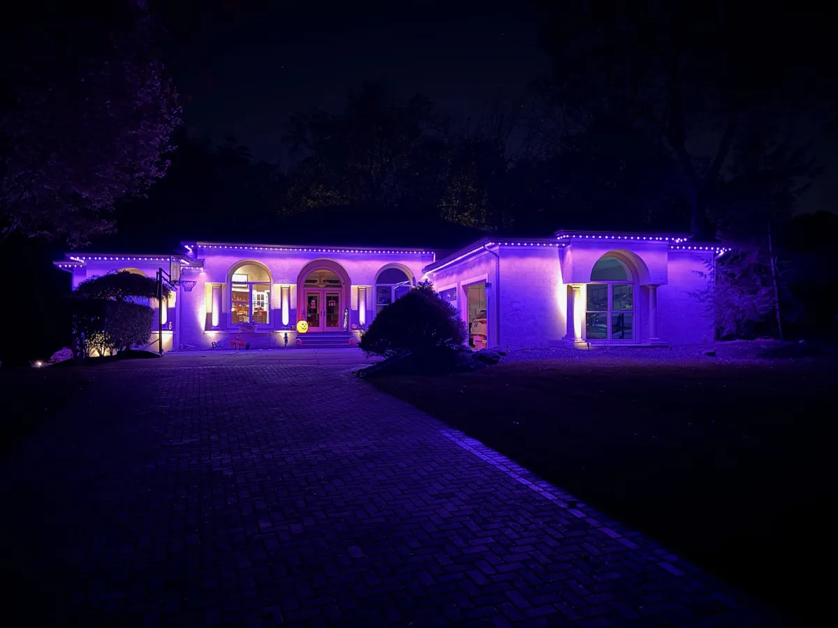 Purple permanent accent lights illuminating stucco mansion at night