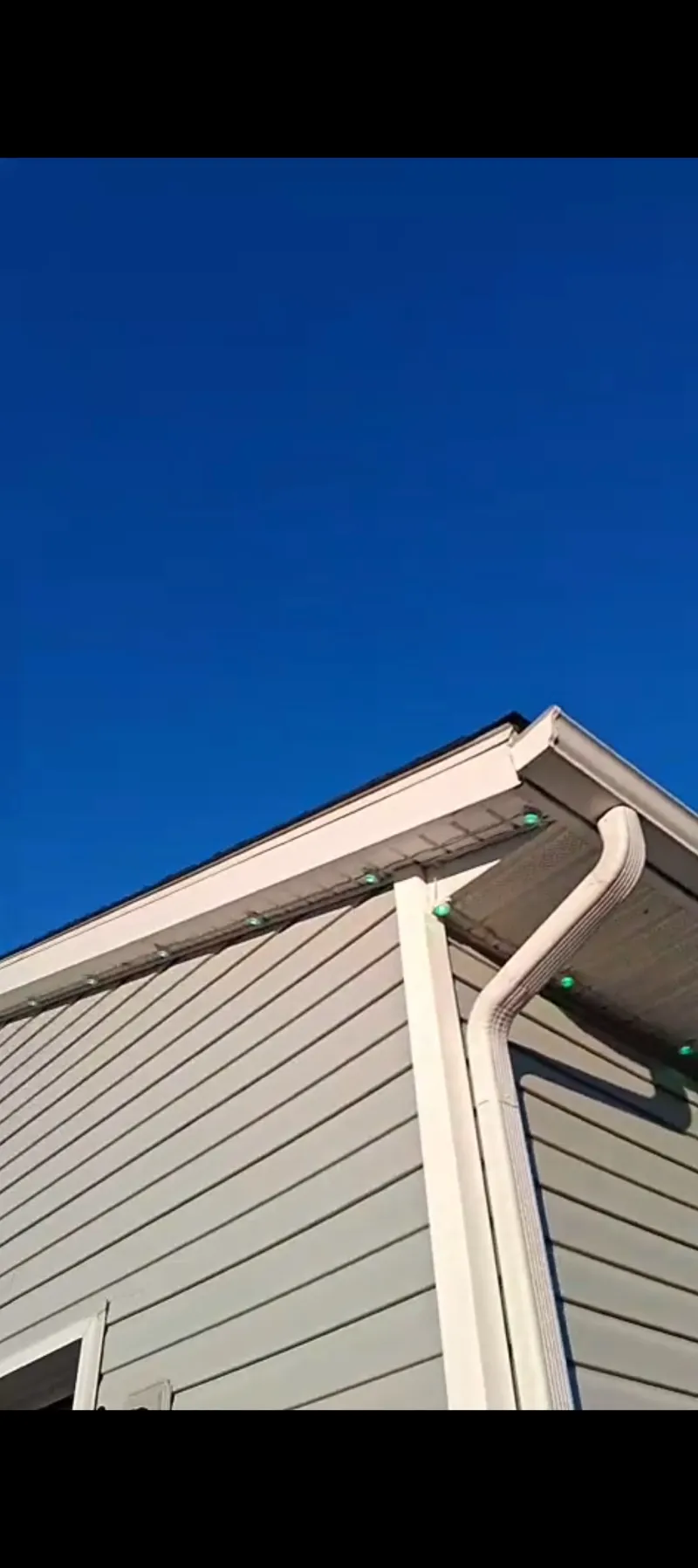 Govee outdoor lights mounted on a Columbus home in daytime, showing the visible green LED bulbs and wires along the soffit